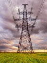 High-voltage power lines passing through a green field, on the background of a beautiful cloudy sky Royalty Free Stock Photo