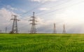 High-voltage power lines passing through a green field, on the background of a beautiful cloudy sky Royalty Free Stock Photo