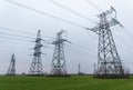 High-voltage power lines passing through a green field of wheat, on the background of a cloudy sky Royalty Free Stock Photo