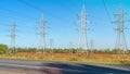 High-voltage power lines and power pylons near the highway. Transmission towers in industrial landscape. High voltage electric