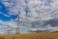 High voltage power lines and power pylons in a agricultural landscape on a sunny day with cirrus clouds in the blue sky Royalty Free Stock Photo