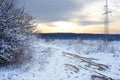 High-voltage power lines at sunrise in a winter. Bad muddy winter road. Beautiful winter landscape. Royalty Free Stock Photo