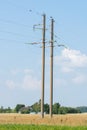 High-voltage power lines in wheat field meadow and blue sky background. High voltage electric transmission towers Royalty Free Stock Photo