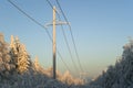 High-voltage power transmission line passing through a glade in the winter forest Royalty Free Stock Photo