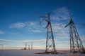 High-voltage power transmission line with towers in field in winter at sunset in the evening Royalty Free Stock Photo