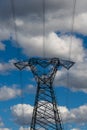 High voltage pylons against a blue sky with white clouds. Royalty Free Stock Photo