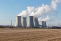 High voltage pylons with a cooling tower of a nuclear power plant view into a blue sky with clouds. Royalty Free Stock Photo