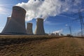 High voltage pylons with a cooling tower of a nuclear power plant view into a blue sky with clouds. Royalty Free Stock Photo