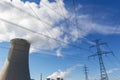 High voltage pylons with a cooling tower of a nuclear power plant view into a blue sky with clouds. Royalty Free Stock Photo