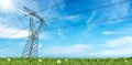 High Voltage Tower on a Green Meadow against a Blue Sky with Clouds Royalty Free Stock Photo
