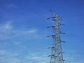 High voltage tower power line against blue sky.