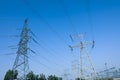 High voltage towers against blue sky on sunny day, low angle view Royalty Free Stock Photo