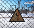 High-voltage transformer substation behind barbed-wire chain-link fence with Danger High Voltage sign. Royalty Free Stock Photo