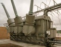 High voltage transformer tank and turrets and grey sky Royalty Free Stock Photo