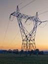 High voltage transmission power line tower with orange sunset background Royalty Free Stock Photo