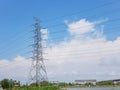 High voltage transmission tower with power line over blue sky and white cloud background Royalty Free Stock Photo