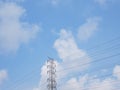 High voltage transmission tower with power line over blue sky and white cloud background Royalty Free Stock Photo