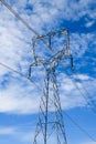 High voltage transmission tower and wires against blue sky with broken clouds Royalty Free Stock Photo