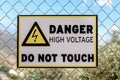 A high voltage warning sign on the fence on sky background Royalty Free Stock Photo