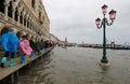 high water in Venice in Italy and people walking over the walkways and ancient building Royalty Free Stock Photo