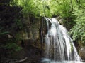 High waterfall from a mountain river in the green spring forest Royalty Free Stock Photo