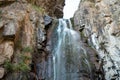 a high waterfall among rocky mountains a waterfall with a strong stream flows.