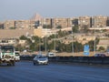 The high way near a block of old houses with the great pyramid of Giza in the background behind the buildings