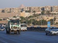 The high way near a block of old houses with the great pyramid of Giza in the background behind the buildings