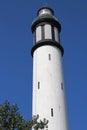 High of a white lighthouse on a background of cloudless blue sky
