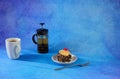 A high white mug with tea, a full teapot and a plate with sponge cake in chocolate crumb with cherry Royalty Free Stock Photo