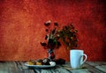 A high white mug with tea, a plate with three fresh eclairs, a vase with herbarium and a small gift box on a wooden table Royalty Free Stock Photo