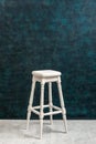 High white wooden stool on a blue green plaster wall background wiht copy space vertical. Bar chair on the background of Royalty Free Stock Photo