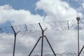 High wire fence with barbed wire against blue sky background. Border, protection zone Royalty Free Stock Photo