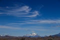 High wispy cirrus clouds filling the blue sky in Patagonia. With a glacier covered peak in the foreground