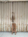 high wooden chair in front of a dirty shop rolling door