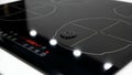 Closeup of a sleek black induction cooktop with illuminated digital controls and multiple cooking zones highlighting modern Royalty Free Stock Photo