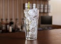 Highball glass with ice and a yellow tube on the wooden bar