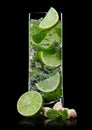 Highball glass of Mojito summer alcoholic cocktail with ice cubes mint and lime on black with cane sugar and lime slice Royalty Free Stock Photo