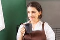 Higher angle of beautiful caucasian barista woman sits blanky and looks outside window in breaking time while holding hot coffee Royalty Free Stock Photo