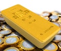 The highest standard gold bar lies on the coins