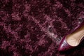 highheeled shoe next to scuff marks on a plush burgundy carpet