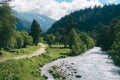 Highland landscape with road and river with green pine forest