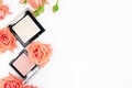 Highlighter and pink face blush kit. Professional cosmetics products with blooming flowers isolated on white backdrop. Copy space