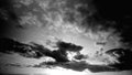 Highly contrasted black and white cloudscape in timelapse. The sun shines behind the clouds moving from left to right.