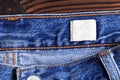 Highly detailed closeup of blank grungy leather label on worn blue denim with orange seams, good for background - Image Royalty Free Stock Photo