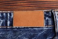 Highly detailed closeup of blank grungy leather label on worn blue denim with orange seams, good for background - Image Royalty Free Stock Photo