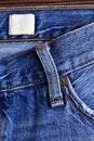 Highly detailed closeup of blank grungy leather label on worn blue denim with orange seams, good for background - Image Royalty Free Stock Photo