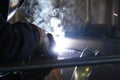 A highly skilled welder welds a metal structure at an assembly plant