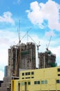 Highrise tower crane and new unfinished residential townhouse under construction, yellow building front view. and sky background. Royalty Free Stock Photo