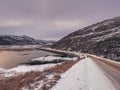 Highway between the Arctic hills. Northern winter road turn on the road. Magenta polar sunset